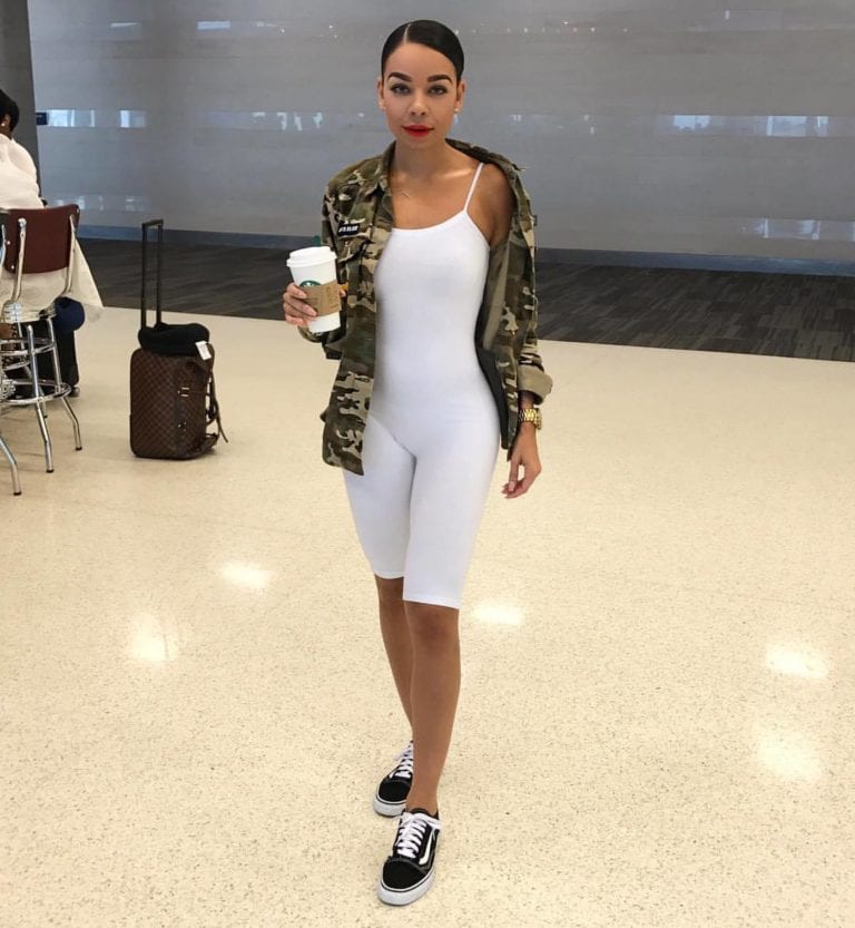 Woman in white bodysuit, camo jacket.
