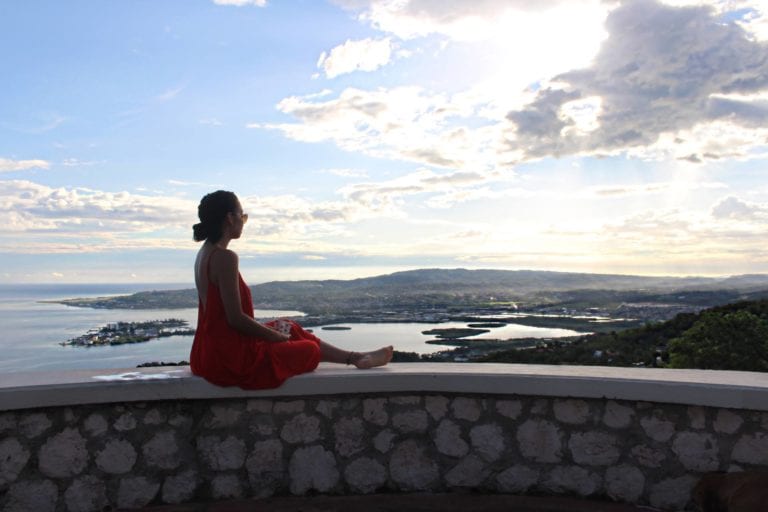 Woman in red dress overlooking bay.