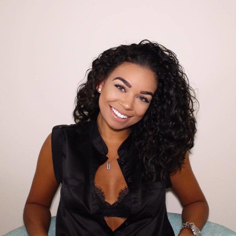 Woman smiles in black top.